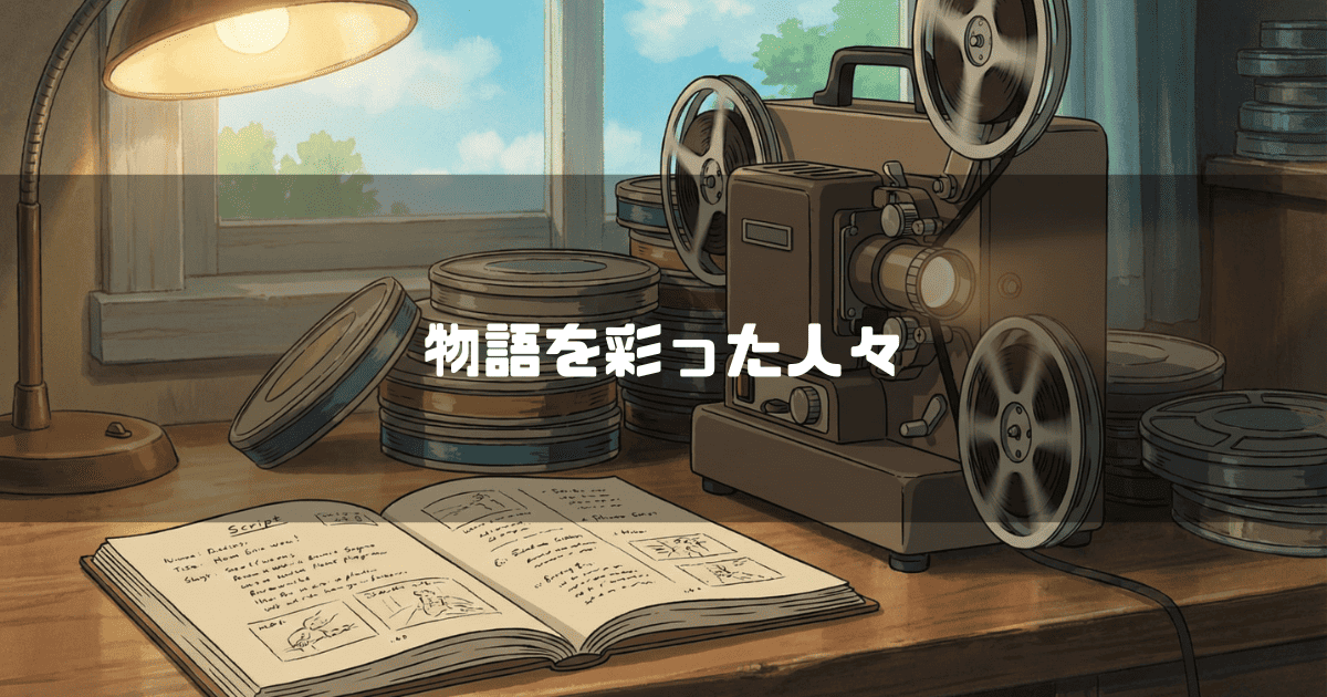 窓際の木製の机の上に置かれた古い映写機、山積みのフィルムリール、そして開かれた絵コンテ。文字内容：「物語を彩った人々」。