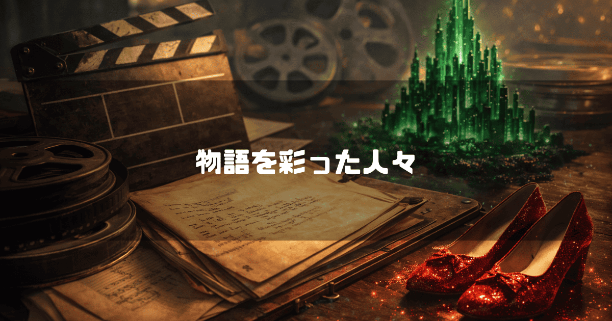 机の上に置かれたカチンコ、フィルムリール、台本、光り輝く赤い靴、ミニチュアのエメラルドシティ。文字内容：「物語を彩った人々」。